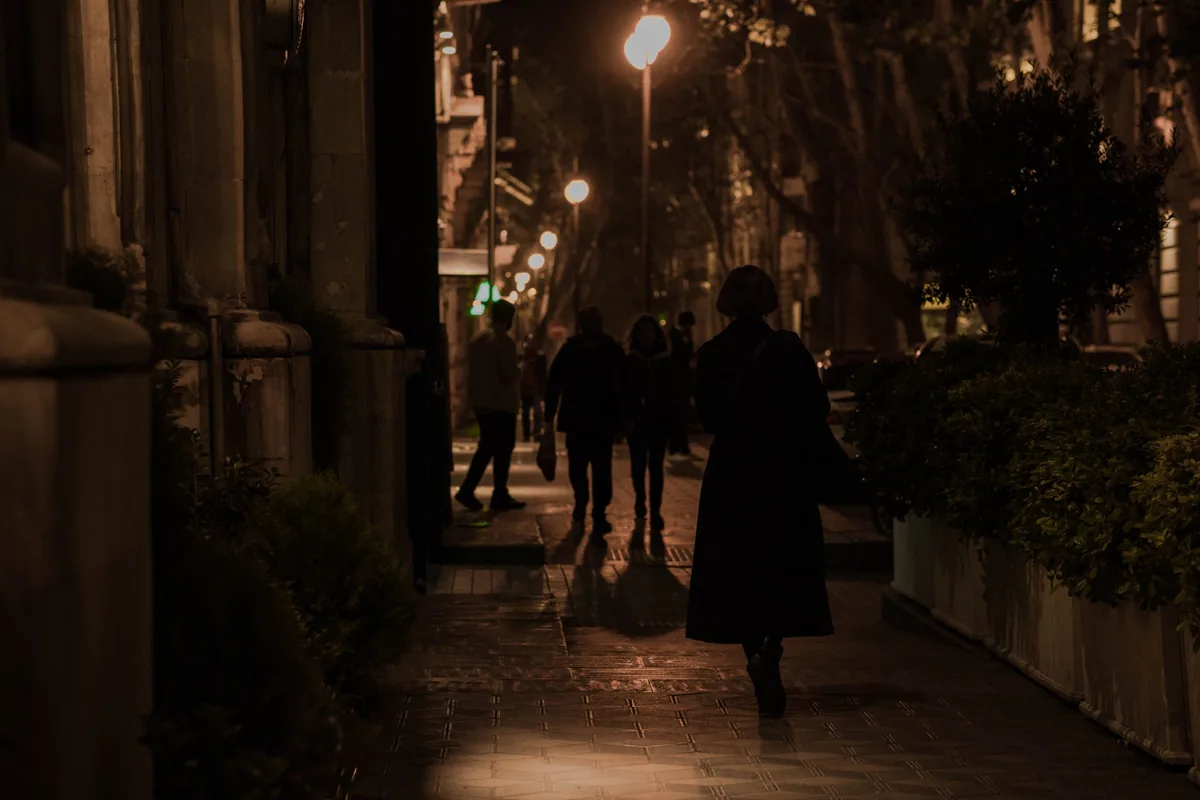 stalking-adwokat-plock Kobieta idąca nocą ulicą, w tle sylwetki przechodniów – stalking, adwokat Płock.